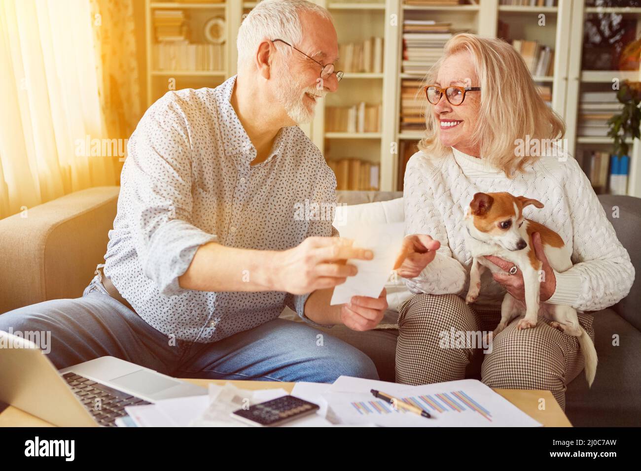 Due anziani con un cane ordinare le ricevute per la contabilità a casa Foto Stock