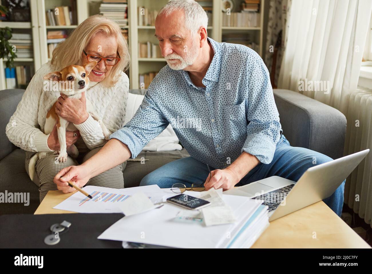 Coppia anziana con un cane che fa contabilità insieme e pianificare il finanziamento della loro fornitura di vecchiaia Foto Stock
