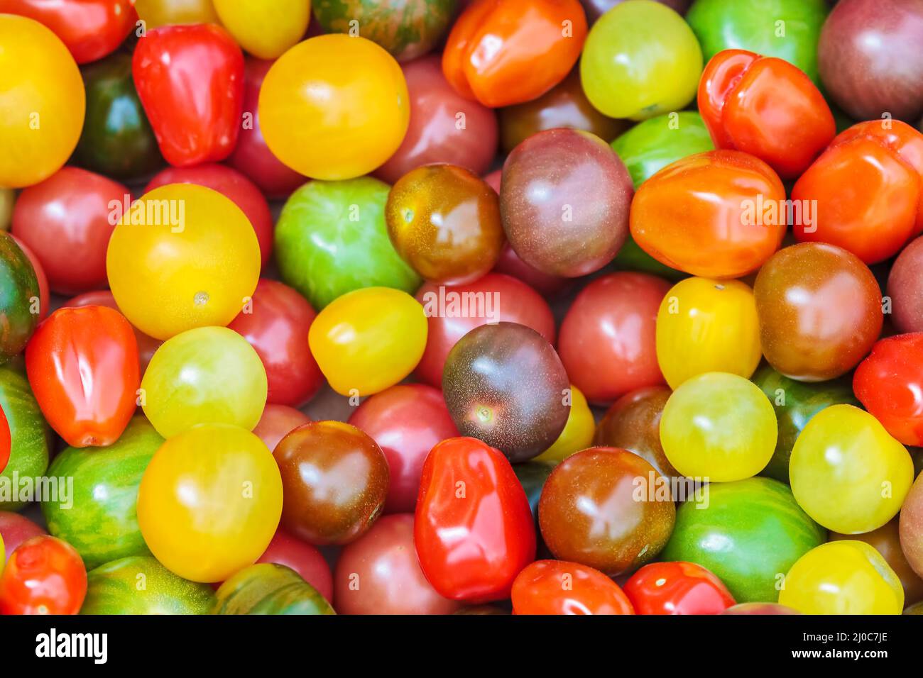 Pomodori ciliegini freschi in diversi colori in mostra in un mercato di alimentari Foto Stock