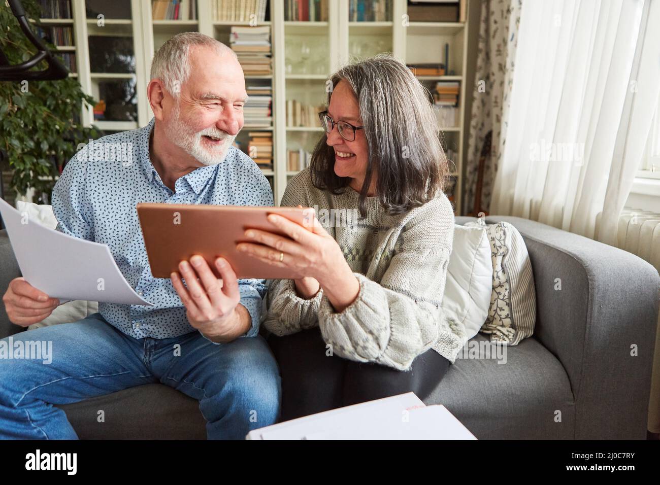 Gli anziani con i computer tablet sono contenti del finanziamento della loro pensione e fornitura di vecchiaia Foto Stock