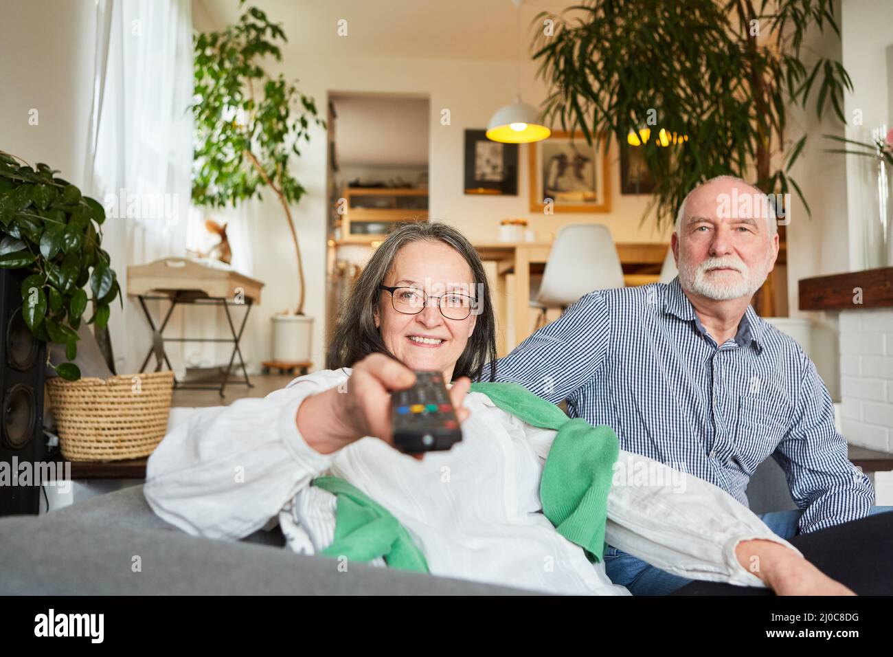 Coppia anziana che guarda con il telecomando della TV mentre zapping nel salotto di casa Foto Stock