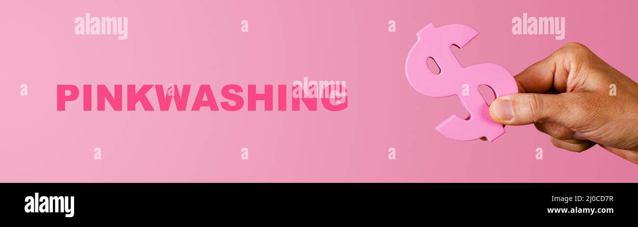 il testo pinkwashing e la mano di un uomo che afferra un segno rosa dollaro su uno sfondo rosa, in un formato panoramico da usare come banner web o intestazione Foto Stock