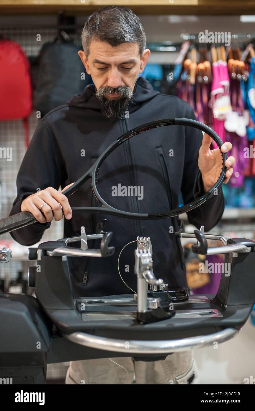 Stringing macchina. Tennista che fa il racket che stringe nella sua officina Foto Stock