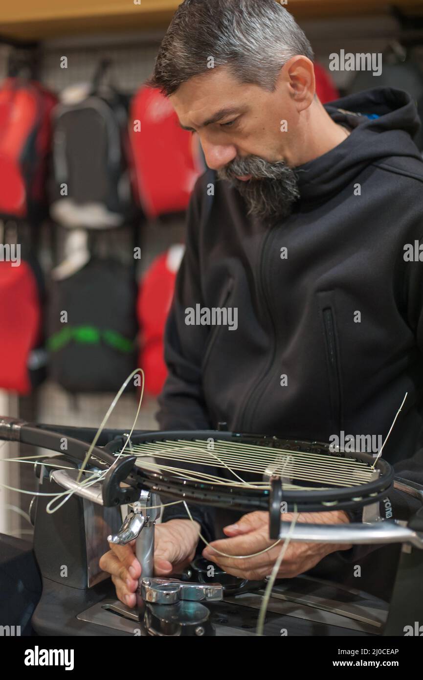 Stringing macchina. Tennista che fa il racket che stringe nella sua officina Foto Stock