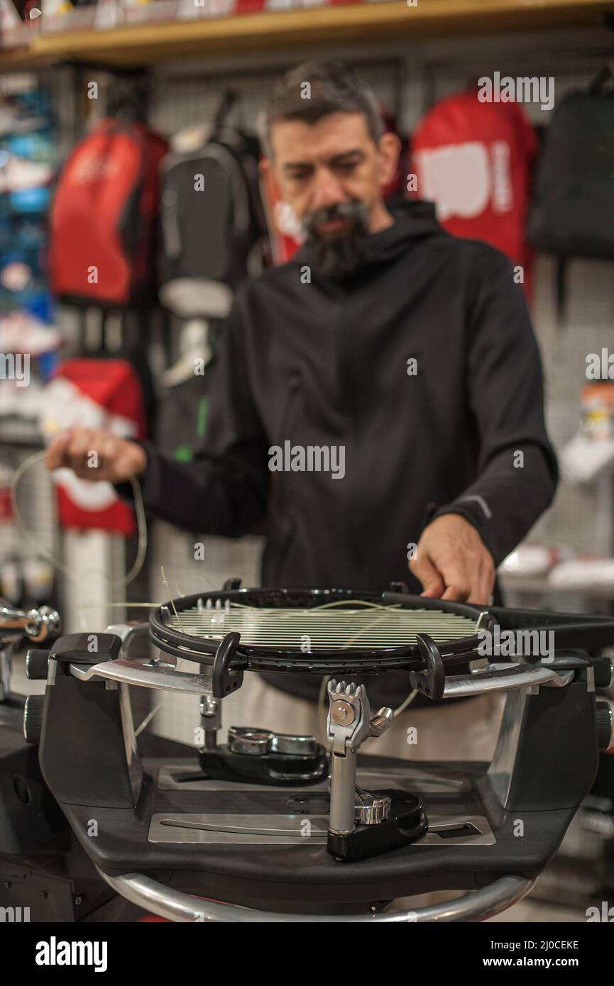 Stringing macchina. Tennista che fa il racket che stringe nella sua officina Foto Stock
