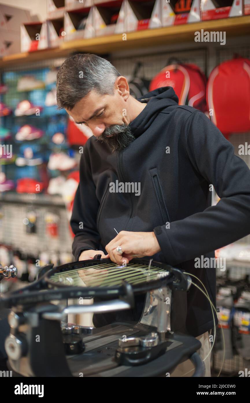 Stringing macchina. Tennista che fa il racket che stringe nella sua officina Foto Stock