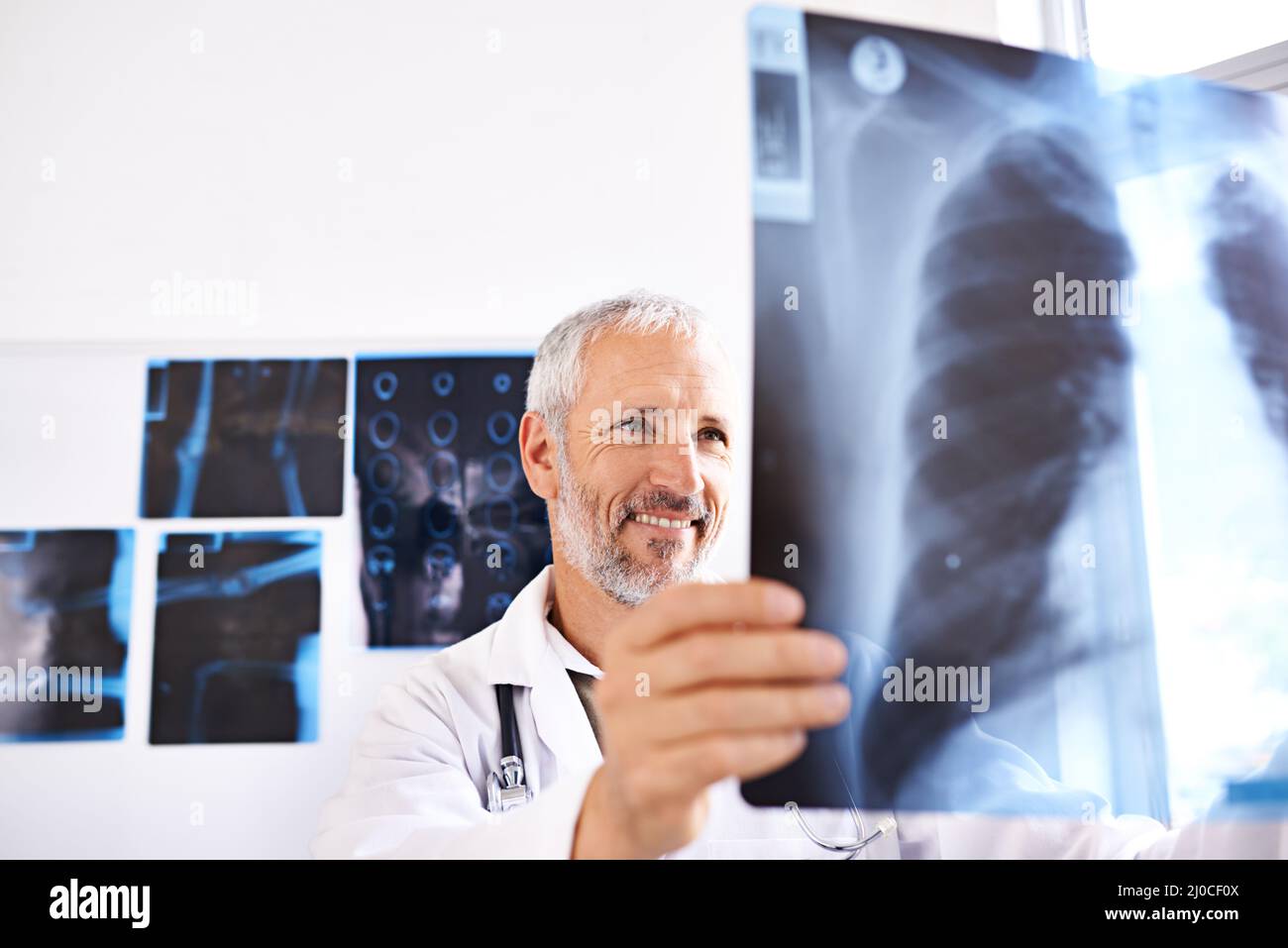 Tutto sembra essere in ordine qui. Scatto di un medico maschio maturo sorridente mentre si guarda un'immagine radiografica in un ospedale. Foto Stock