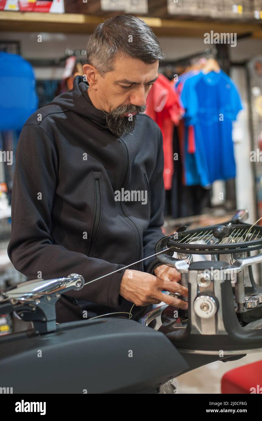 Stringing macchina. Tennista che fa il racket che stringe nella sua officina Foto Stock