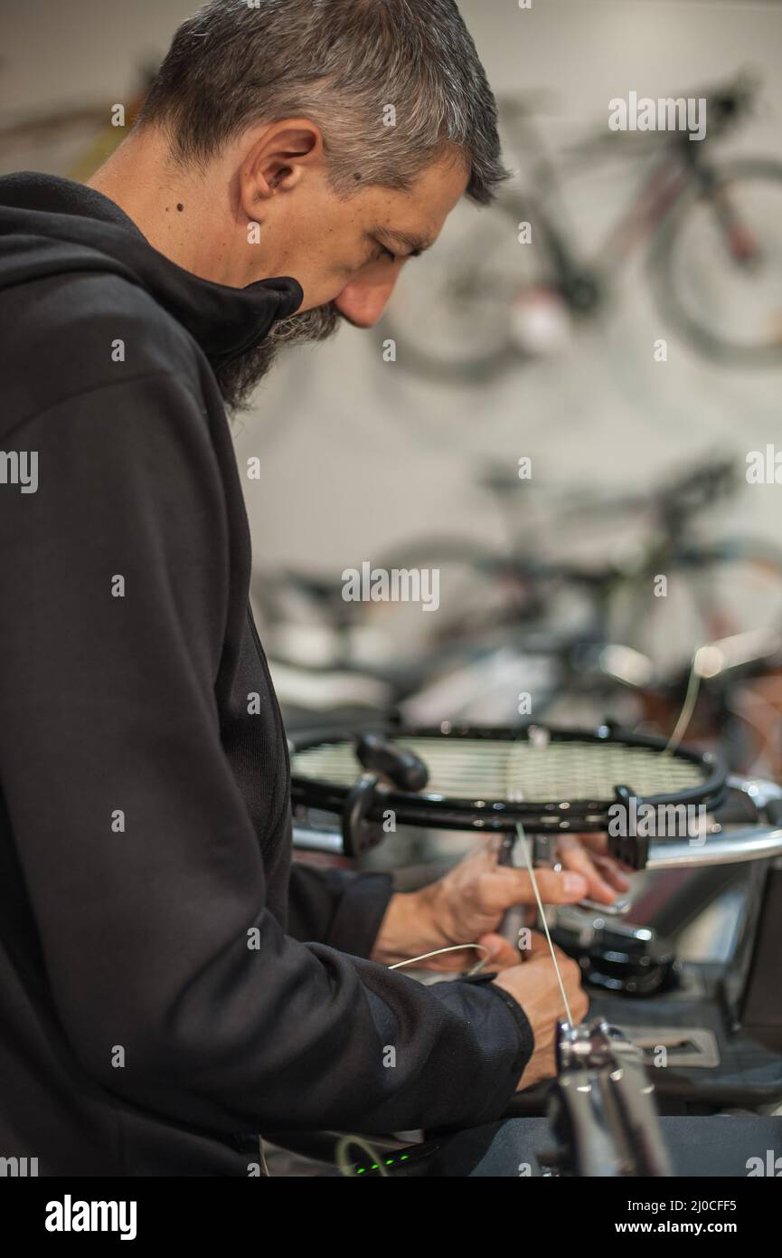 Stringing macchina. Tennista che fa il racket che stringe nella sua officina Foto Stock