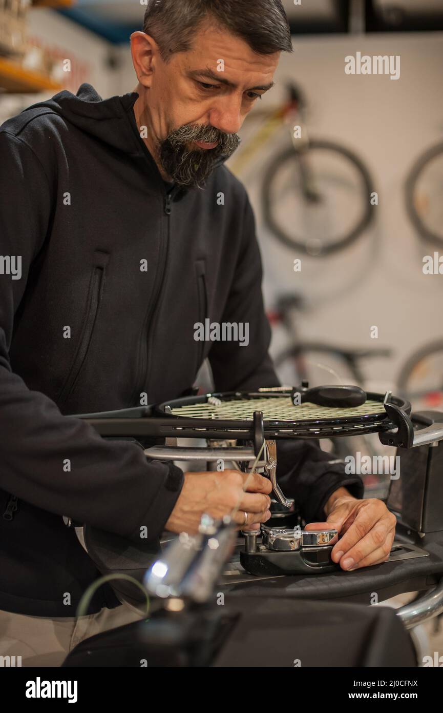Stringing macchina. Tennista che fa il racket che stringe nella sua officina Foto Stock