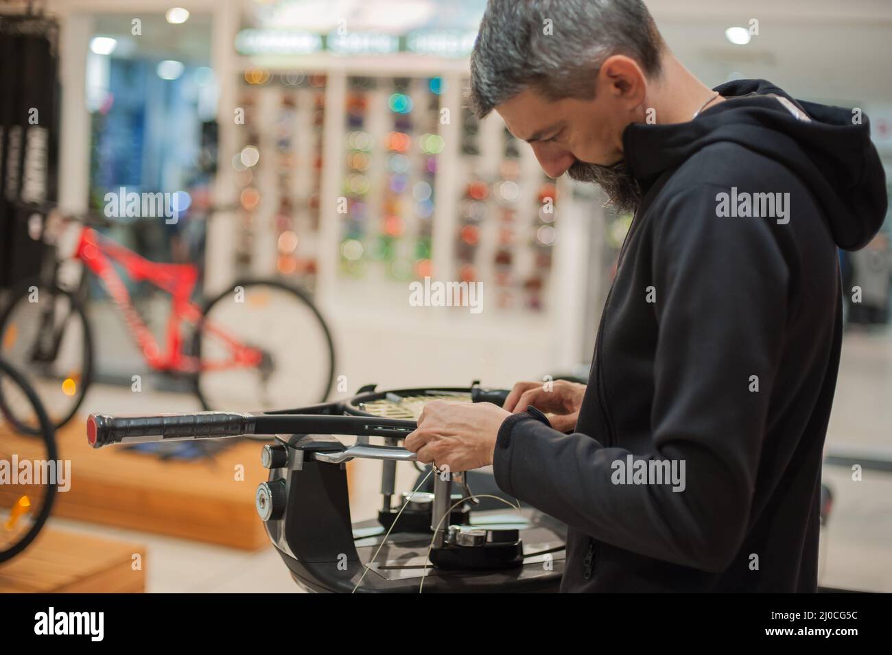 Stringing macchina. Tennista che fa il racket che stringe nella sua officina Foto Stock