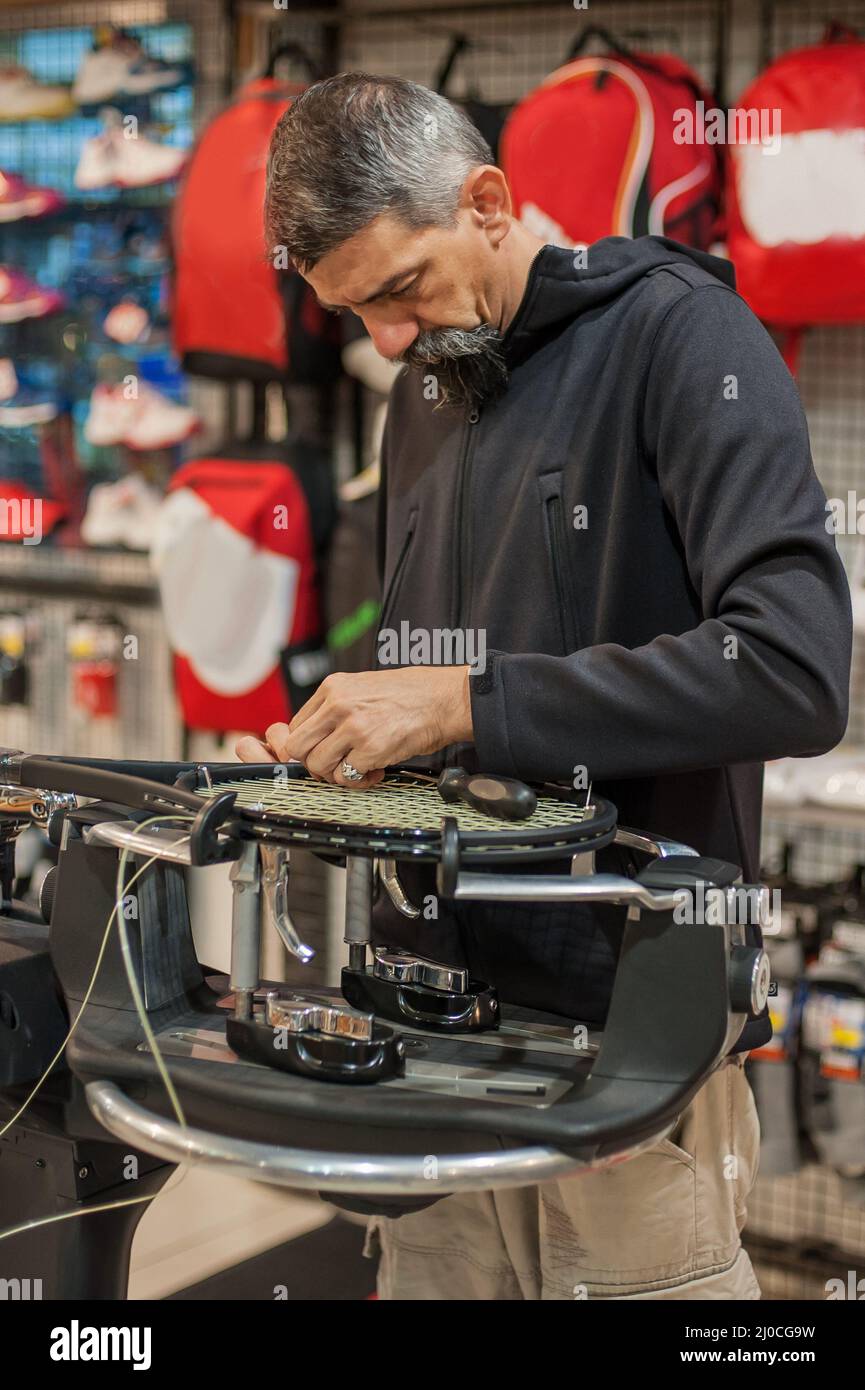 Stringing macchina. Tennista che fa il racket che stringe nella sua officina Foto Stock