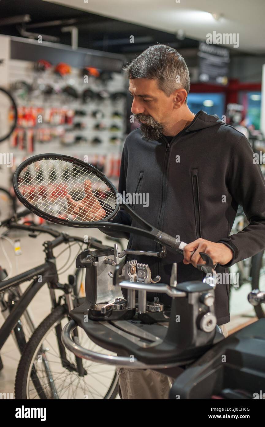 Stringing macchina. Tennista che fa il racket che stringe nella sua officina Foto Stock