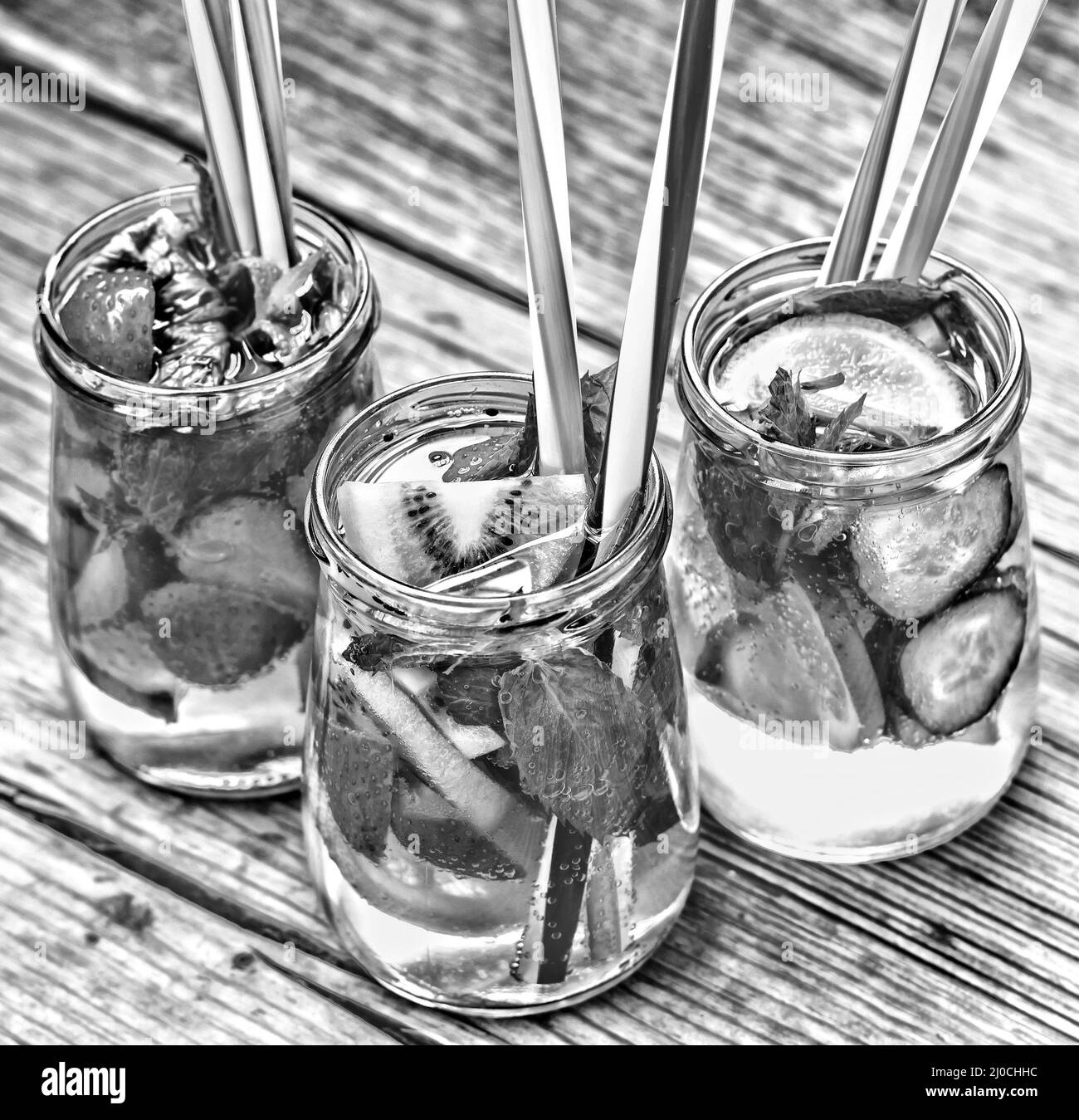 Una varietà di bevande fredde in piccoli flaconi con pezzi di frutta sullo sfondo di legno Foto Stock