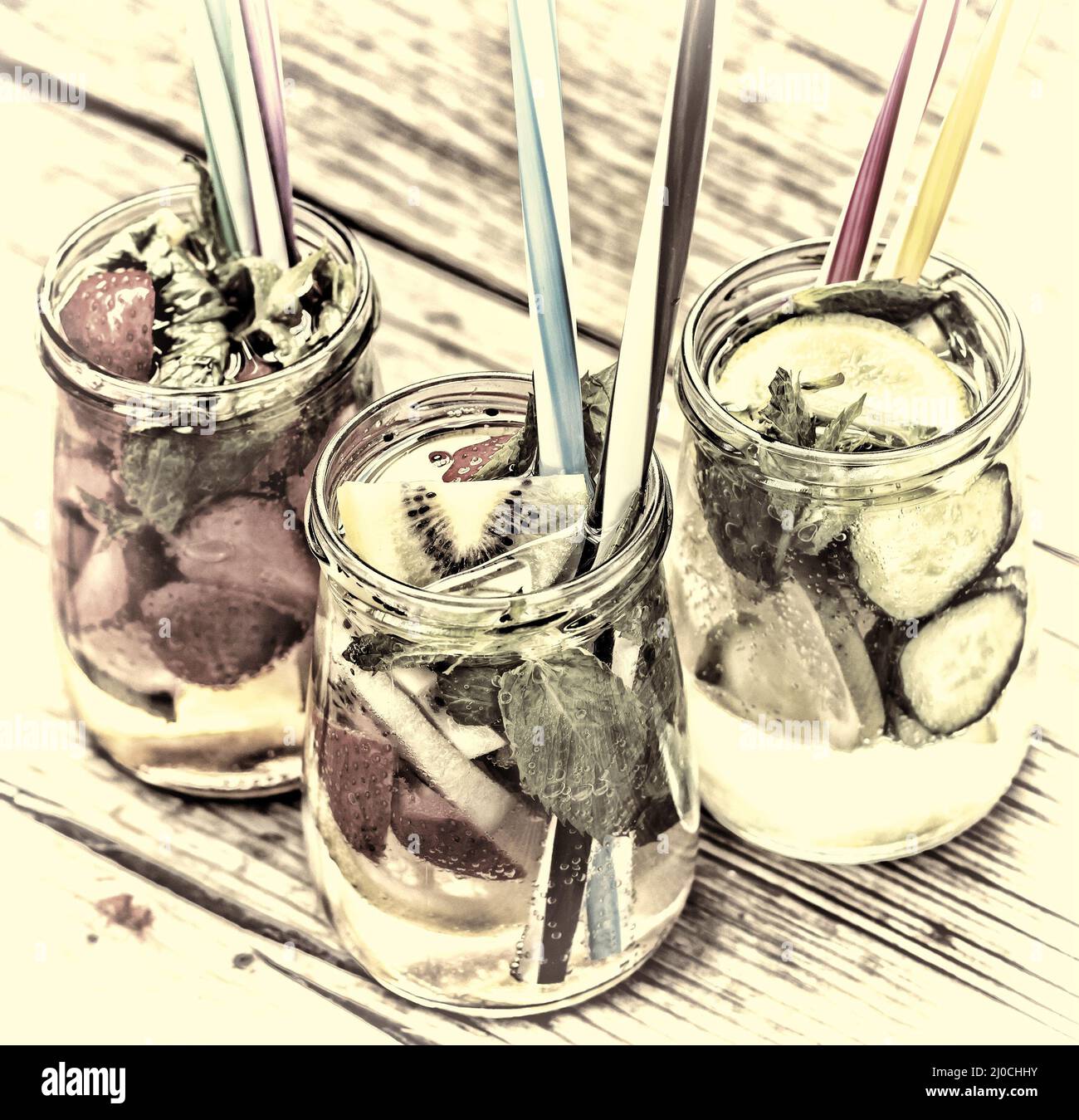 Una varietà di bevande fredde in piccoli flaconi con pezzi di frutta sullo sfondo di legno Foto Stock