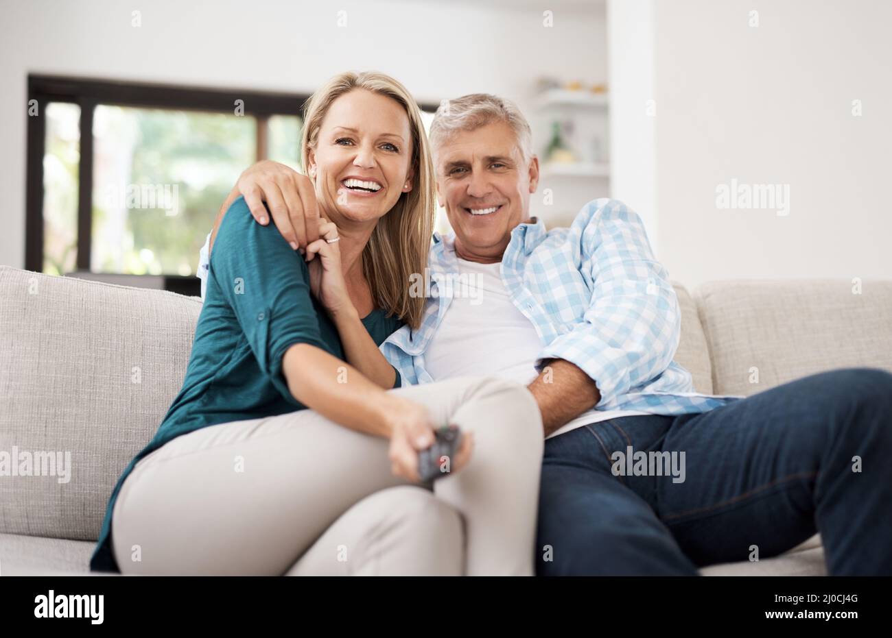 Sostituzione della stazione. Ritratto corto di una coppia matura affettuosa che guarda la televisione insieme a casa. Foto Stock