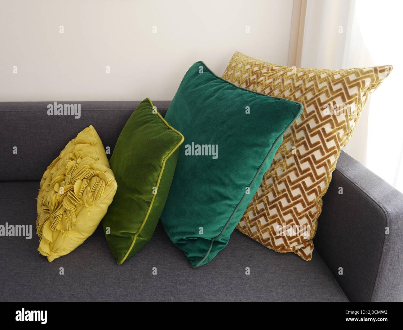 Selezione di eleganti cuscini verdi e gialli su un moderno divano