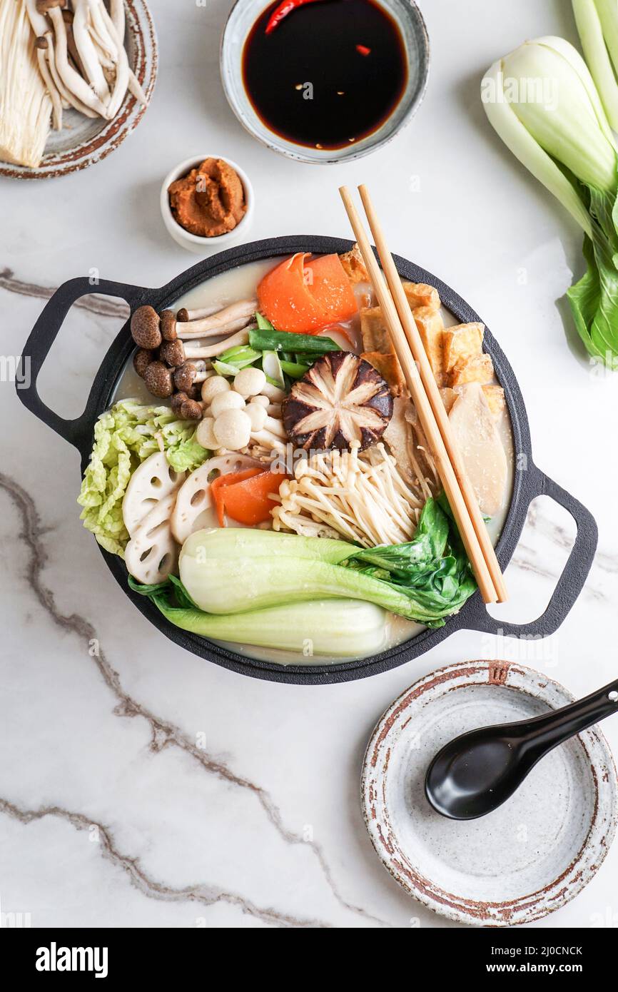 Latte di soia ricetta Hot Pot con cavolo di napa, funghi e maiale affettato sottile cotto in un brodo cremoso e salato di latte di soia. Foto Stock