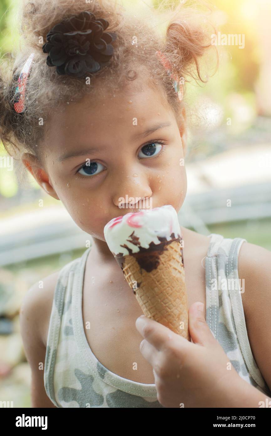 Carina ragazza che mangia il cono gelato sulla strada Foto Stock