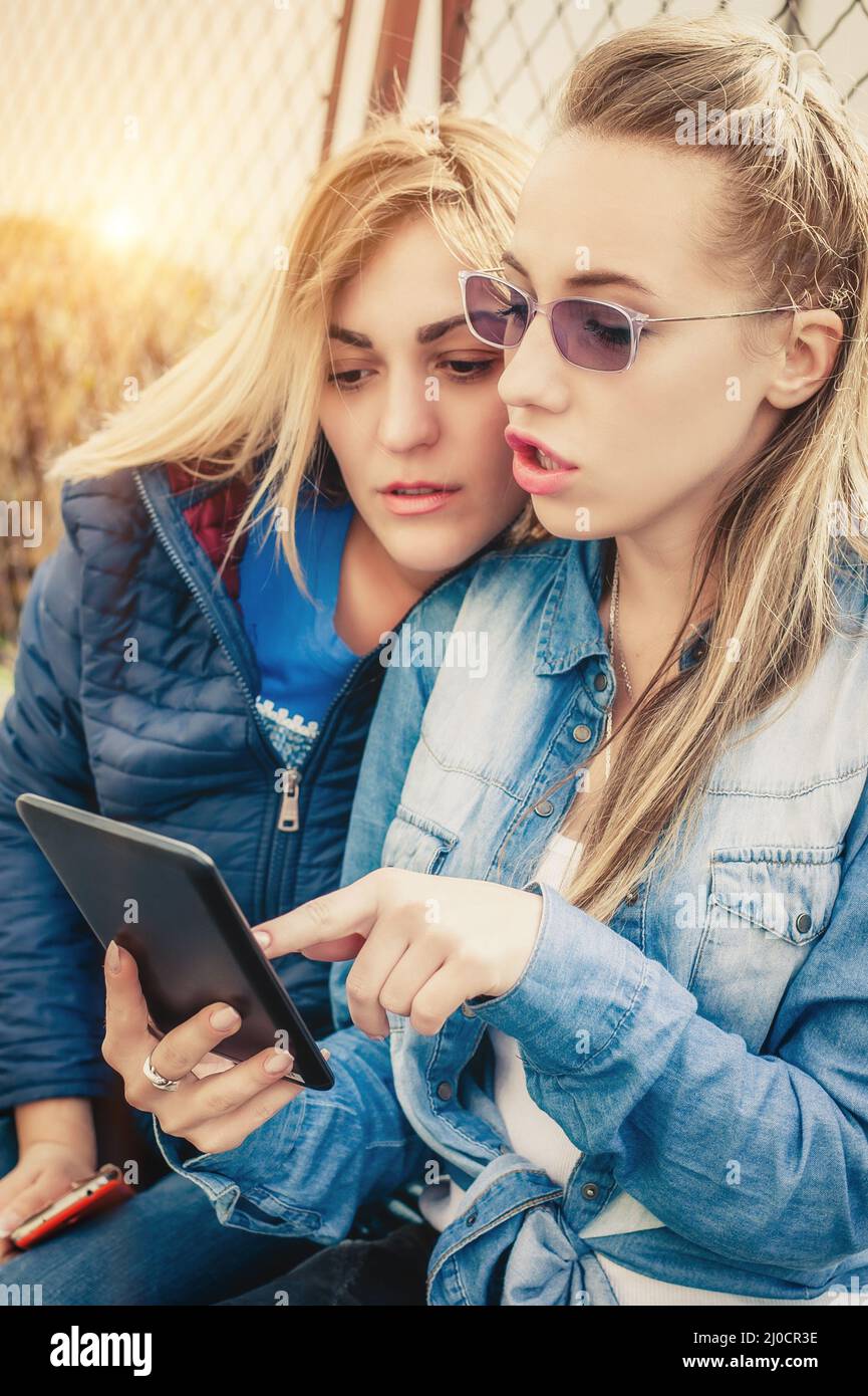 Due amiche esterne che navigano in rete sul tablet pc Foto Stock