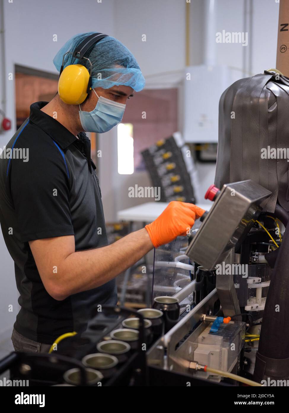 Uomo che lavora con una macchina elettronica per il confezionamento della birra. Foto Stock