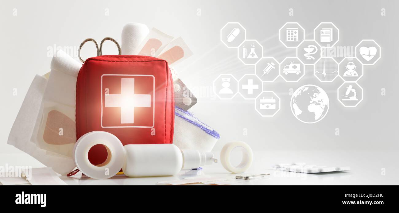 medicina internazionale di soccorso con kit di pronto soccorso su una tabella piena di equipaggiamento di base e icone relative alla medicina. Composizione orizzontale. Anteriore Foto Stock