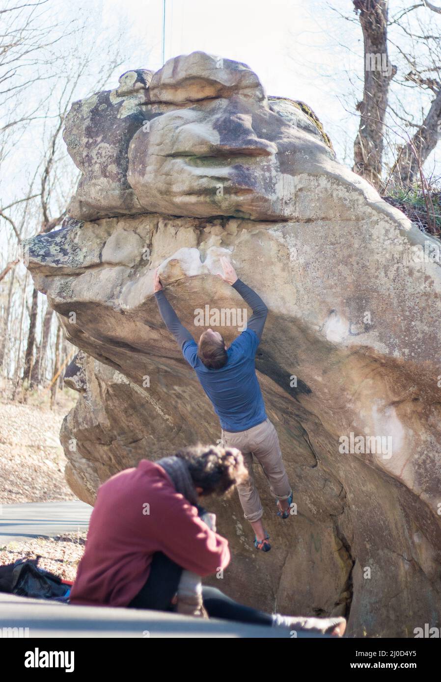 Forte maschio rock climber salta per completare arenaria masso, moglie filma (serie) Foto Stock
