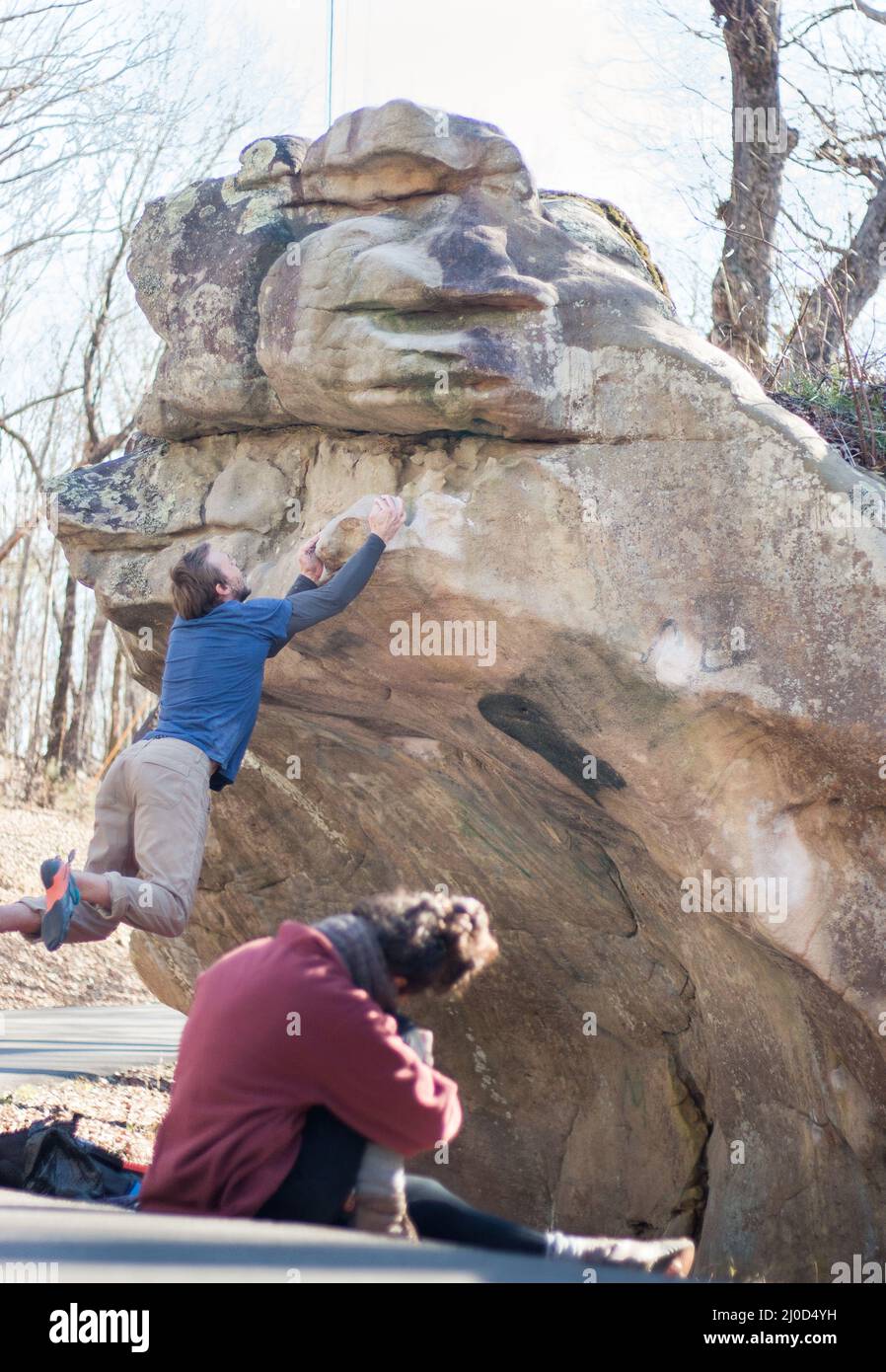 Forte maschio rock climber salta per completare arenaria masso, moglie filma (serie) Foto Stock