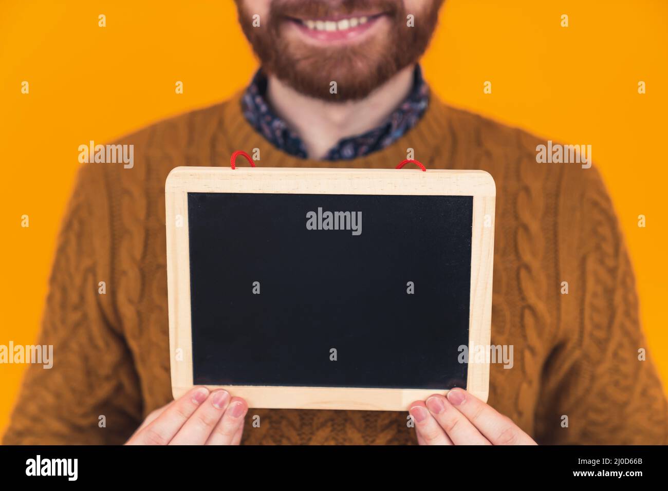 giovane uomo caucasico che tiene una piccola lavagna davanti alla fotocamera. Foto di alta qualità Foto Stock