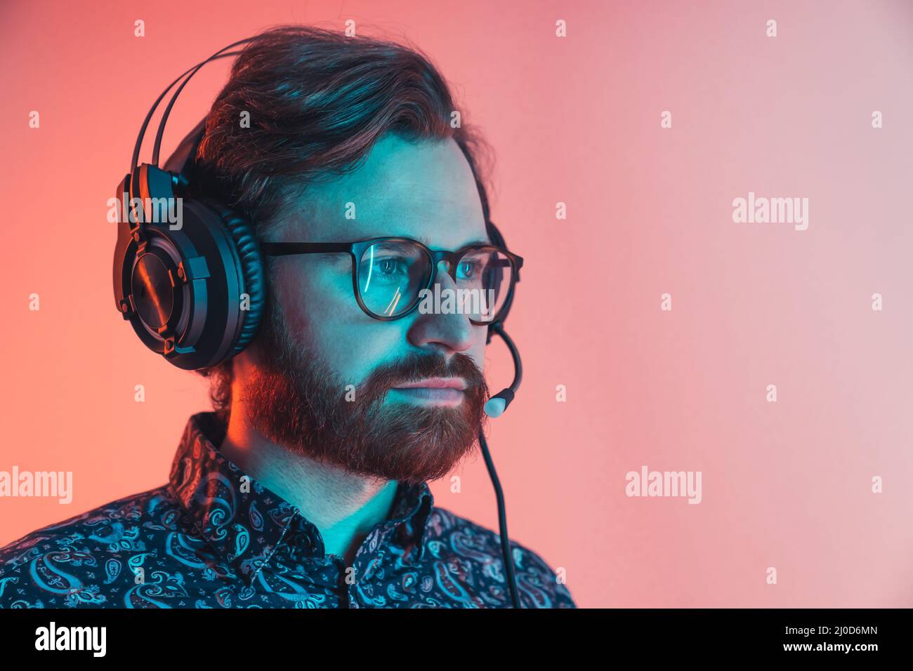 uomo di mezza età che utilizza cuffie con microfono durante un videogioco o una chiamata di lavoro. Foto di alta qualità Foto Stock