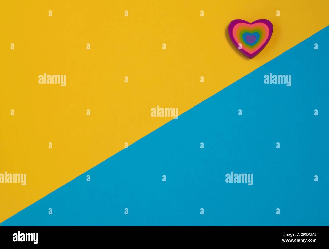 Modello carta San Valentino. Cuore colorato su sfondo blu e giallo. Tessera per il giorno della mamma. Concetto di amore. Spazio di copia Foto Stock