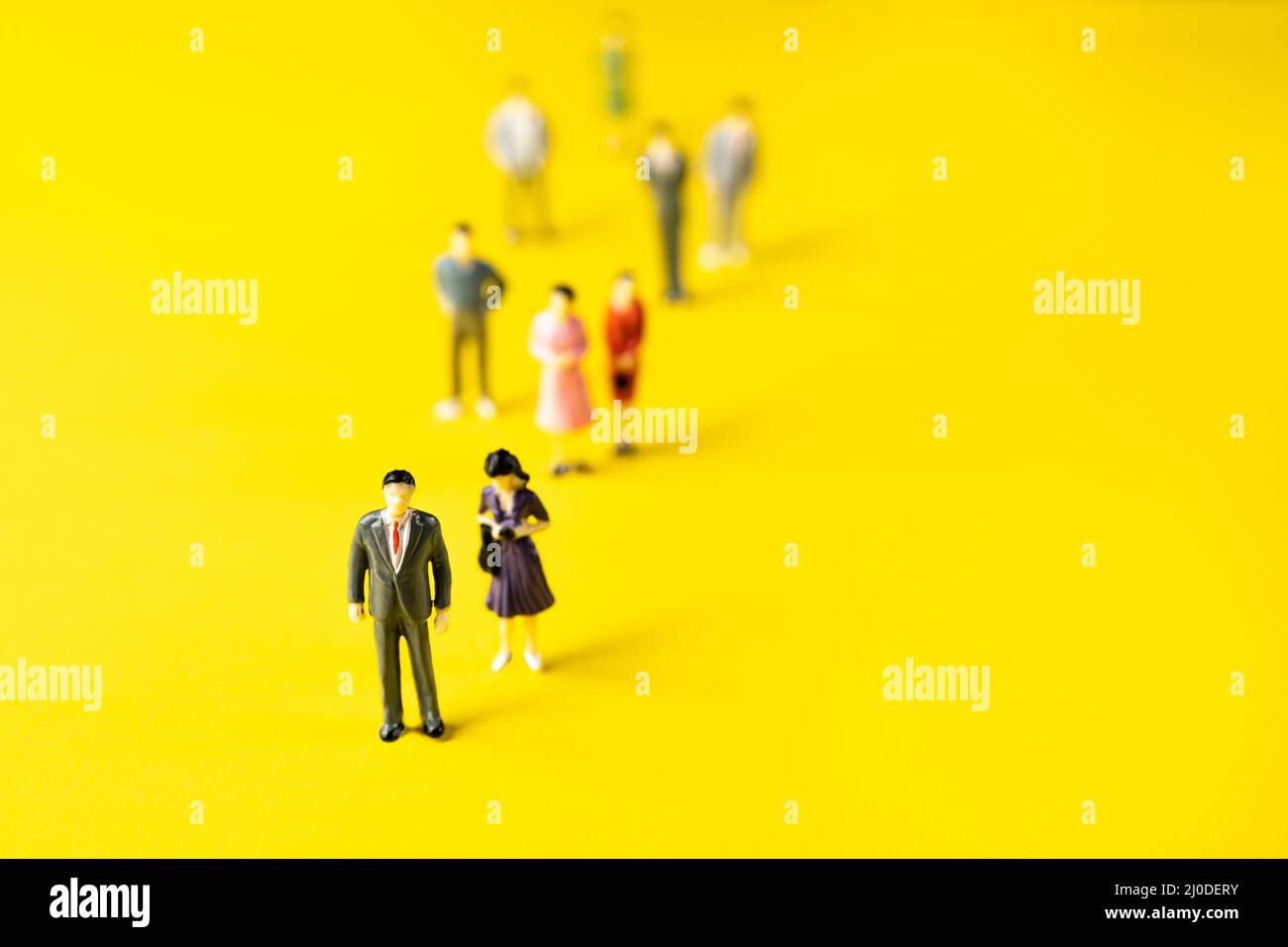 alcune figurine di uomini e donne su una superficie gialla. Foto Stock