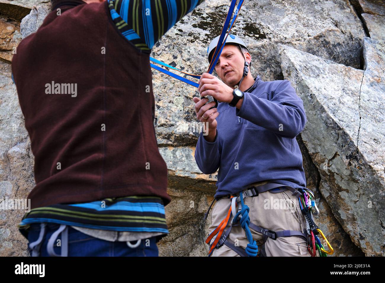 L'istruttore di arrampicata sta insegnando come eseguire la stazione di belay. Foto Stock