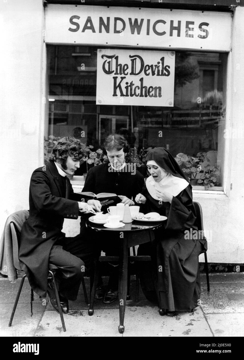Una foto da una serie di immagini di novità umuristiche scattate dal fotografo domenicale Dennis Hutchinson due sacerdoti e una suora gustare il tè pomeridiano al caffè 'The Devils Kitchen'. Circa: 1980 Foto Stock