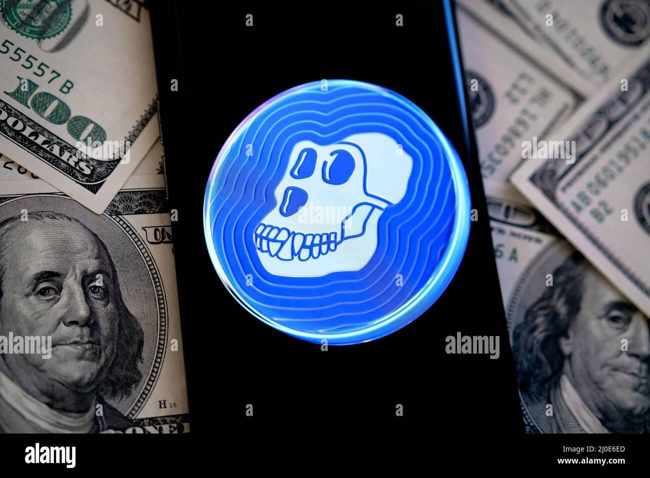 Logo token criptato ApeCoin visualizzato sullo smartphone che viene piazzato in dollari. Nuova criptovaluta da NFT annoiato Ape Yacht Club. Stafford, Regno Unito Foto Stock