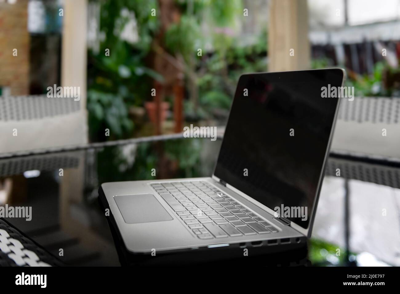 Computer portatile schermo nero vuoto su vegetazione riflettente tavolo  sullo sfondo. Lavorare in remoto fa parte dei nostri giorni Foto stock -  Alamy