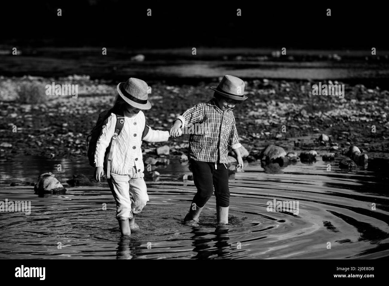 Bambini piccoli carini che tengono le mani e giocano sul fiume insieme. Ragazzo e ragazza del preschooler. I migliori amici. I fratelli più piccoli si uniscono alla natura. Foto Stock