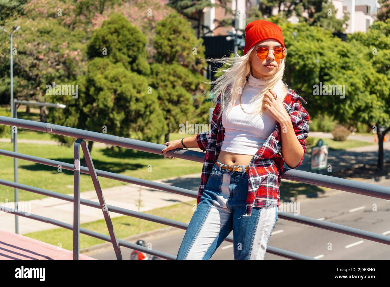 Una bella donna latina urbana appoggiata su una ringhiera del ponte Foto Stock