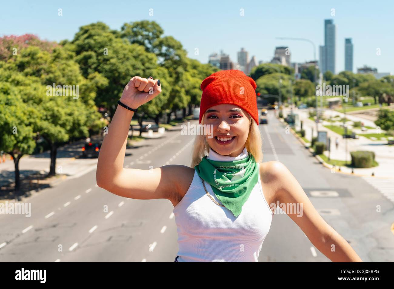 Bella giovane donna con il suo pugno sollevato con una sciarpa verde che simboleggia la lotta femminista per l'uguaglianza e l'aborto legale in America Latina. Concetto Foto Stock