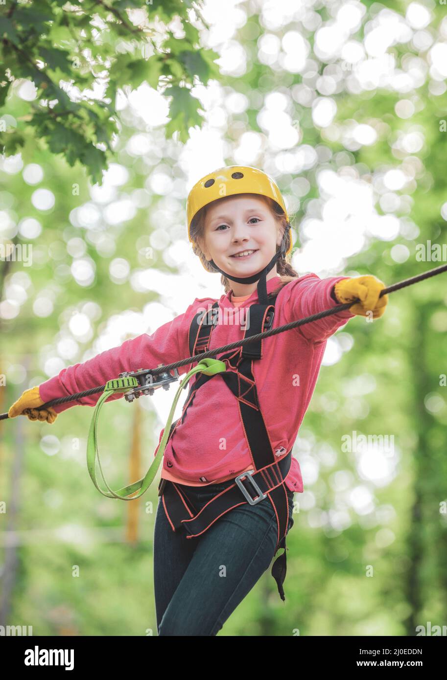 Carino ragazzo della scuola che si gode una giornata di sole in un parco di attività arrampicata avventura. Le opere d'arte raffigurano giochi presso eco resort che includono volata o. Foto Stock