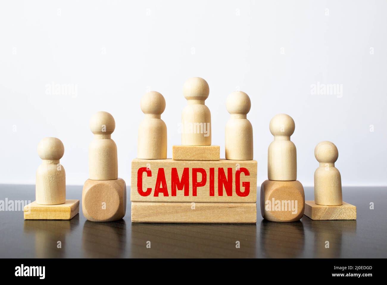 Parola di campeggio su un segno cubo di legno con uno sfondo sfocato di un campeggio in estate. Foto Stock