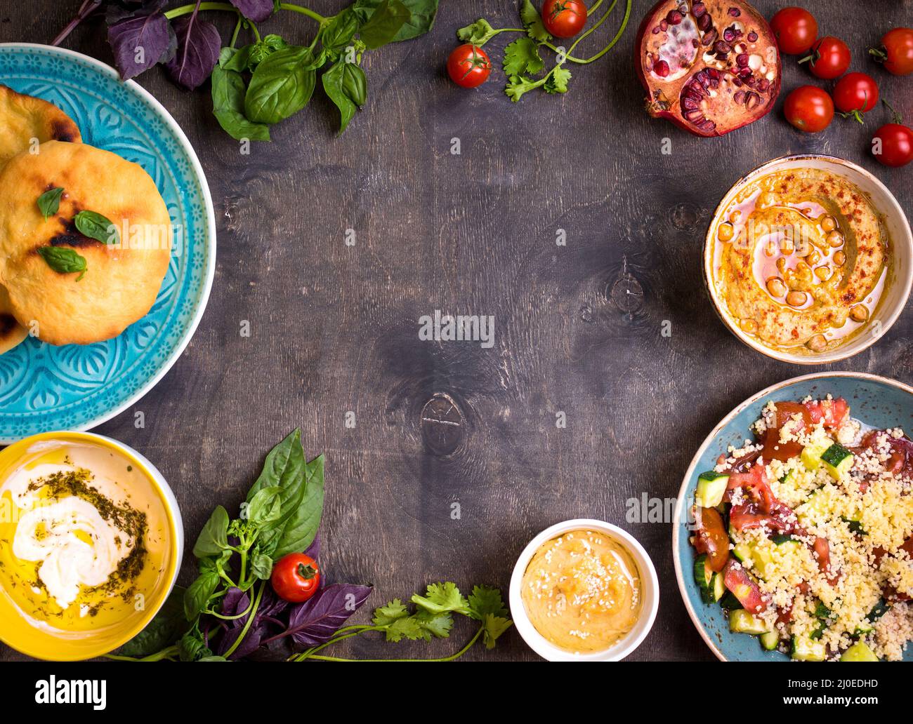 Tabella servita con medio orientale piatti vegetariani. Hummus, la tahina, pitta, cuscus insalata e latticello dip con olio d'oliva Foto Stock