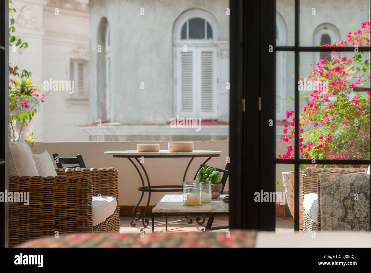 Vista su una terrazza dalla camera da letto, esterno con sedie, piante e luce del mattino. Foto Stock