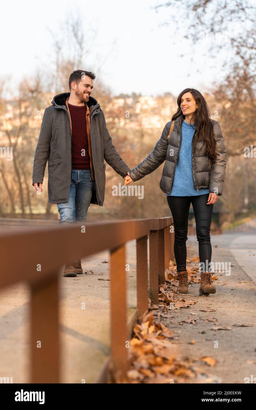 Giovane coppia eterosessuale che cammina in un parco e parla Foto Stock