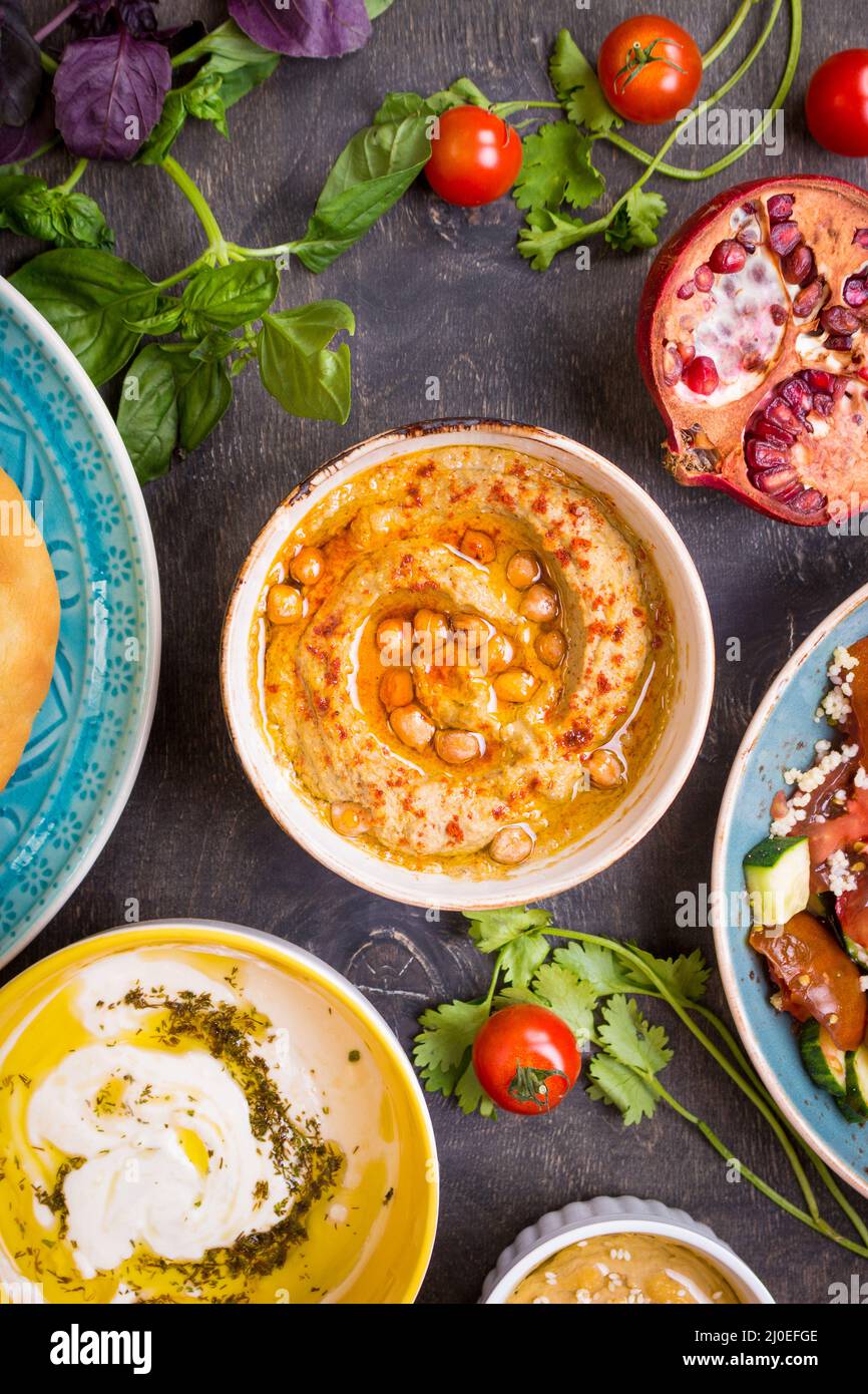 Tabella servita con medio orientale piatti vegetariani. Hummus, la tahina, pitta, cuscus insalata e latticello dip con olio d'oliva Foto Stock