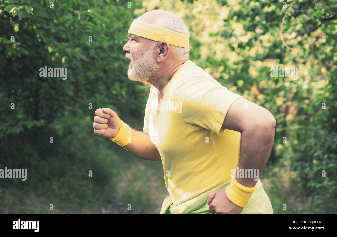 Corridore senior in natura. Allenamento cardio. In funzione nel parco la mattina. Il maschio anziano sta godendo lo stile di vita sportivo. Concetto di stile di vita sano Foto Stock