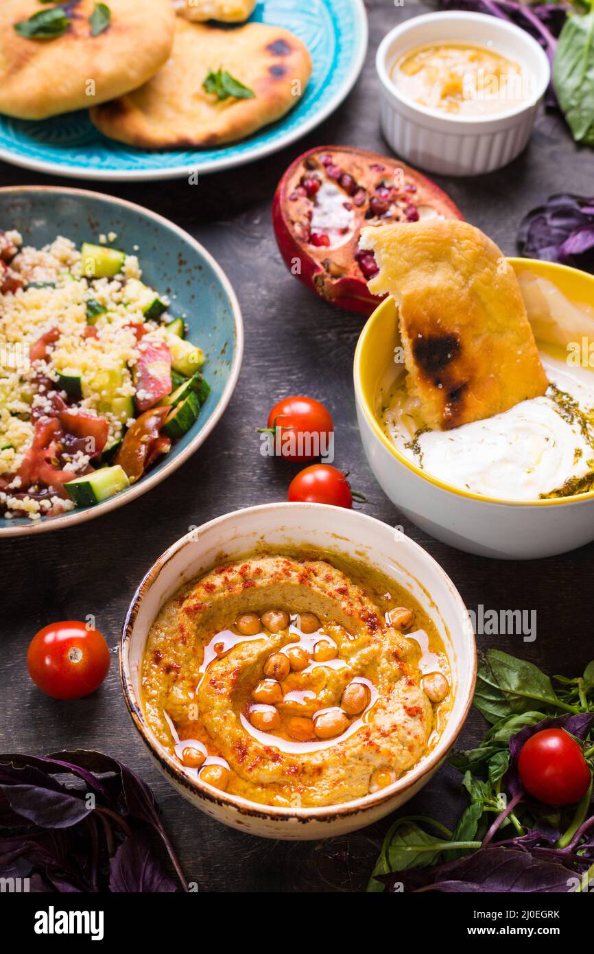 Tabella servita con medio orientale piatti vegetariani. Hummus, la tahina, pitta, cuscus insalata e latticello dip con olio d'oliva Foto Stock