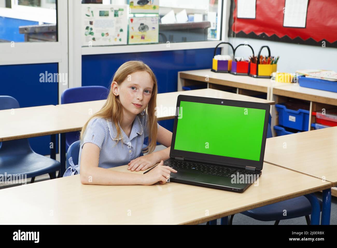 Ragazza della scuola elementare caucasica con un computer con uno schermo verde Foto Stock