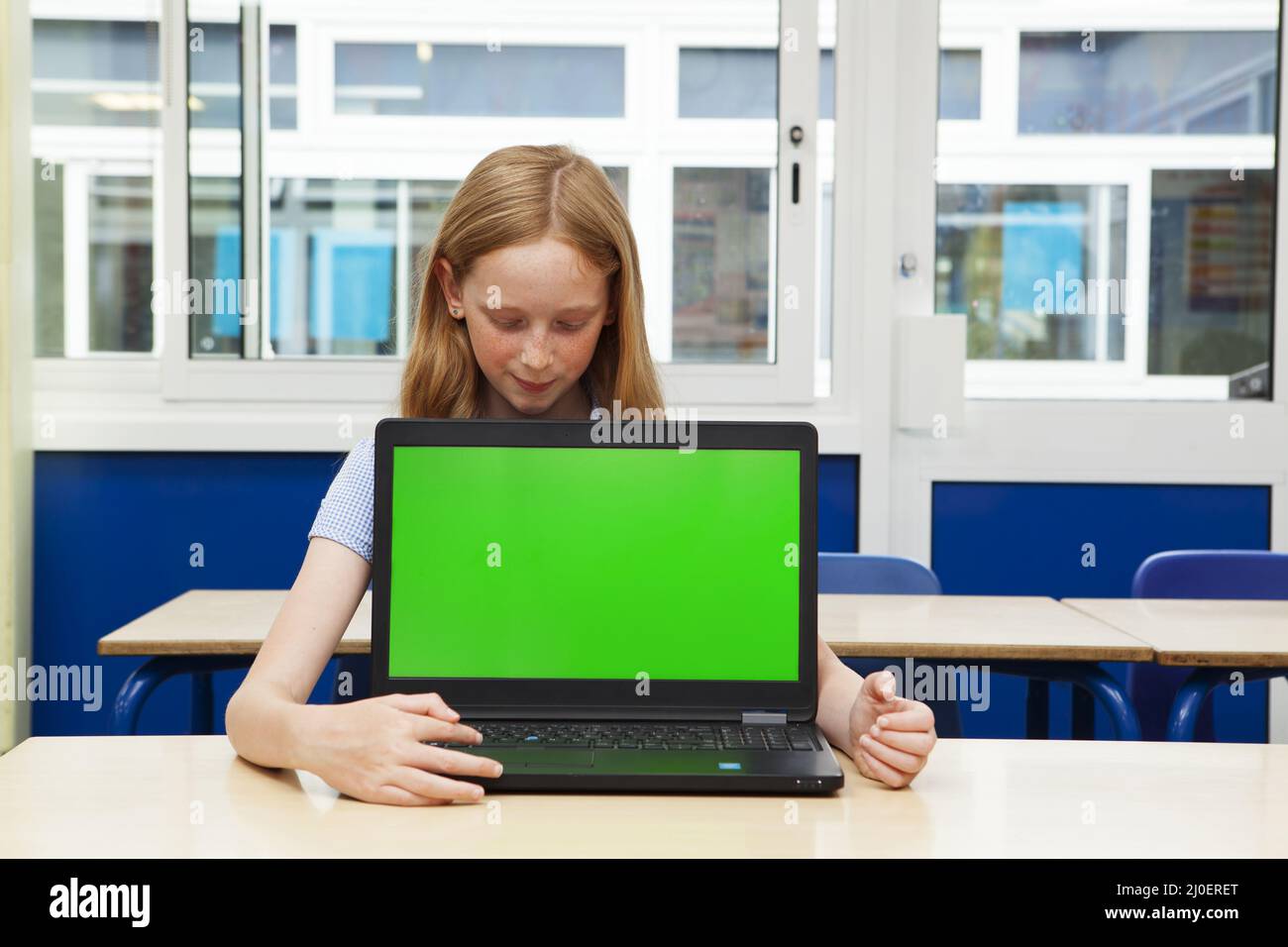 Ragazza della scuola elementare caucasica con un computer con uno schermo verde Foto Stock
