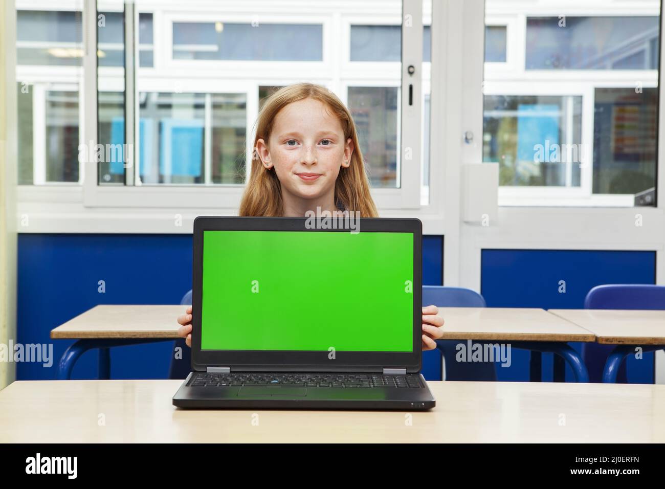 Ragazza della scuola elementare caucasica con un computer con uno schermo verde Foto Stock